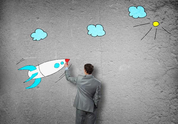 Businessman drawing rocket on wall — Stock Photo, Image