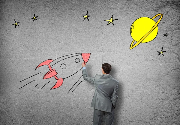 Businessman drawing rocket on wall — Stock Photo, Image