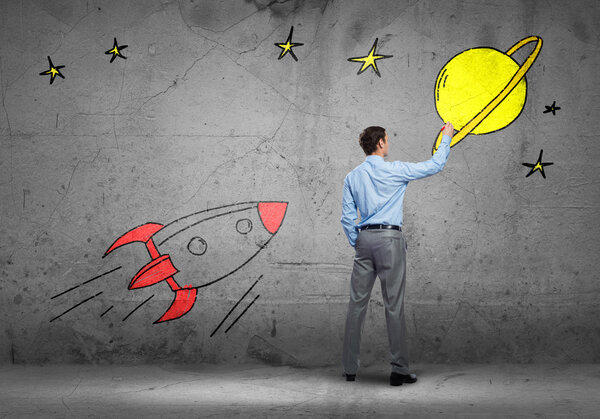 businessman drawing rocket on wall