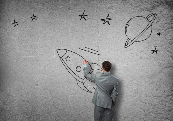 Бизнесмен рисует ракету на стене — стоковое фото
