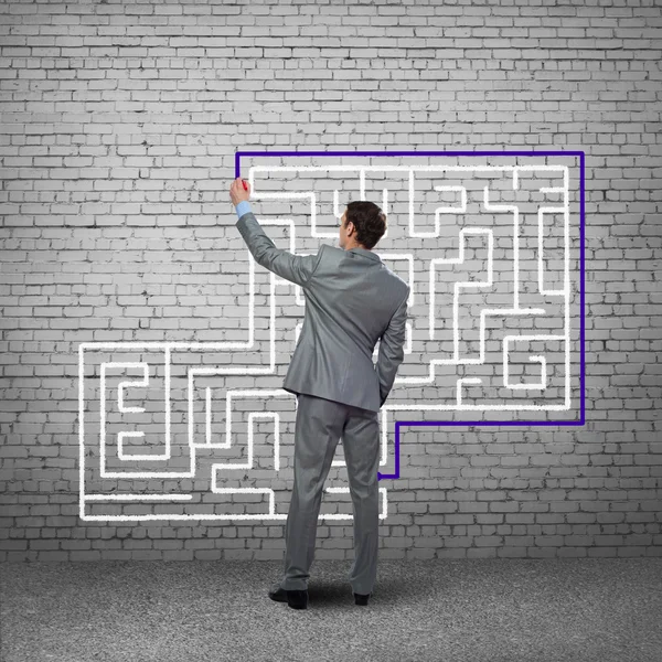 Businessman drawing labyrinth on wall — Stock Photo, Image