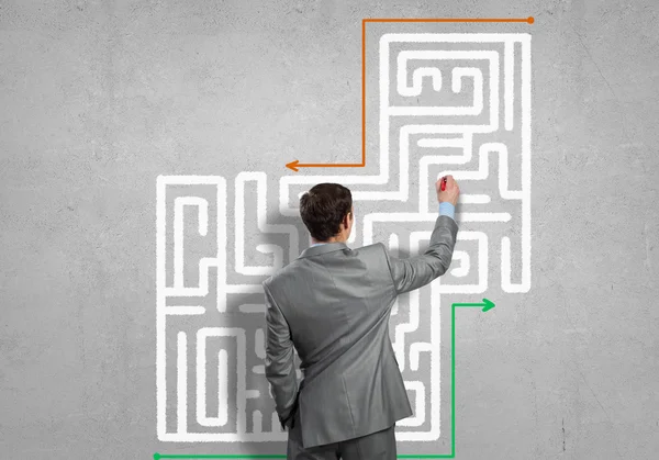 Businessman drawing labyrinth on wall — Stock Photo, Image