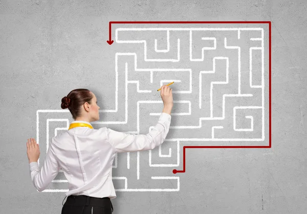 Businesswoman drawing labyrinth on wall — Stock Photo, Image