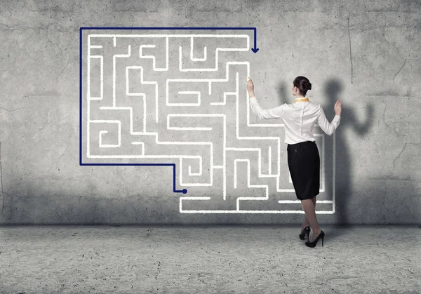 Businesswoman drawing labyrinth on wall — Stock Photo, Image