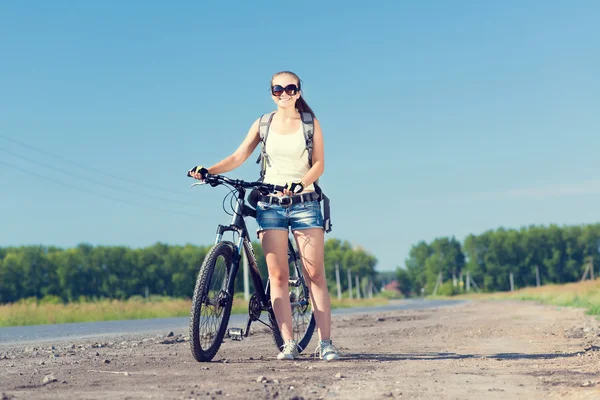 Frau mit Rucksack zu Fuß mit Fahrrad — Stockfoto