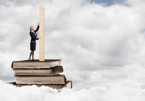 Geschäftsfrau steht auf Bücherstapel — Stockfoto