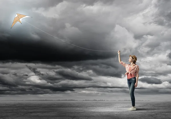 Mädchen in Jeans spielt mit fliegendem Drachen — Stockfoto