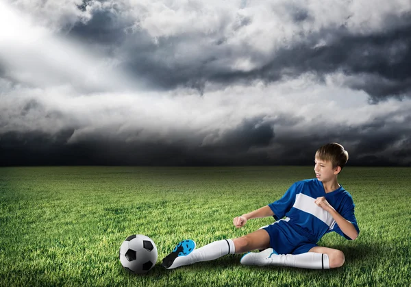 Rapaz chutando bola de futebol — Fotografia de Stock