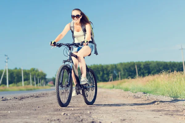Frau mit Rucksack auf Fahrrad unterwegs — Stockfoto