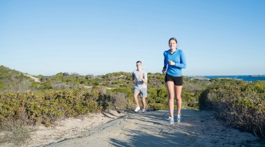 Plaj boyunca çalışan çift