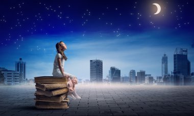 Kitap yığınının üzerinde oturan kız