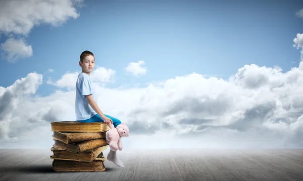 Kind zittend op oude boeken — Stockfoto