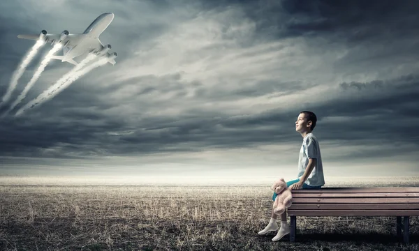 Niño en el banco y avión en el cielo —  Fotos de Stock