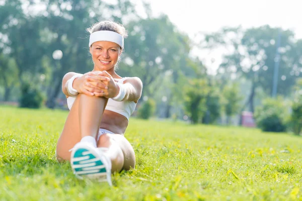 Fitness mladá dívka sedící v parku — Stock fotografie