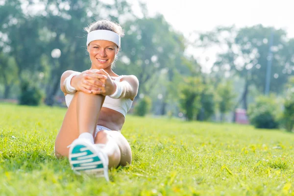 Jeune fille de fitness assis dans le parc — Photo