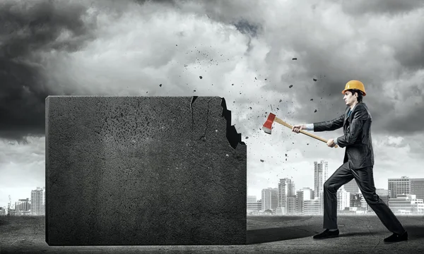 Hombre de negocios en casco rompiendo muro de cemento — Foto de Stock