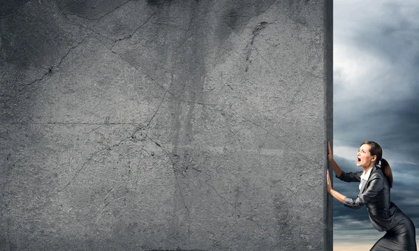 Businesswoman  moving cement wall — Stock Photo, Image