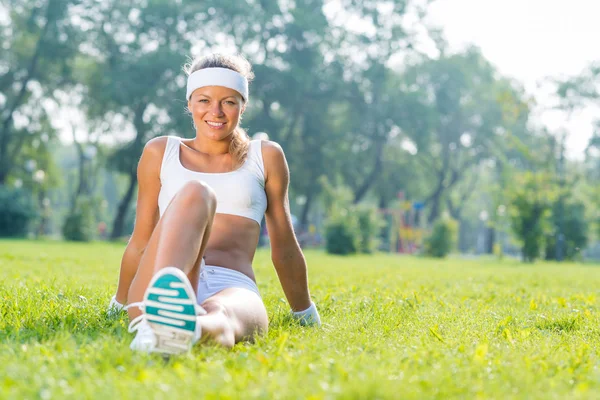 Fitness girl sitting in park — Stock Photo, Image