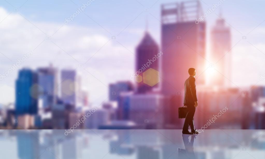 businessman with suitcase looking at sunset