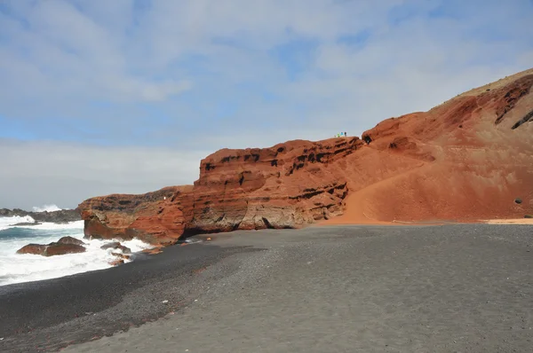 Rote Felsen am schwarzen Lavastrand der spanischen Kanareninsel Lanzarote — Stockfoto