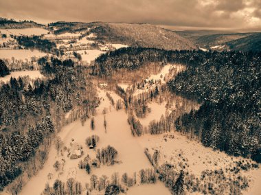 Bir kar yağışı sırasında Stolowe dağlarındaki kış manzarasında güzel panoramik hava aracı manzarası. Stolowe Dağları Ulusal Parkı, Polonya, Avrupa.