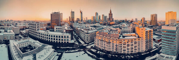 WARSAW, POLAND - JANUARY 31, 2021: Beautiful panoramic aerial drone view on Warsaw City Skyscrapers, PKiN, and Varso Tower under construction and 19th-century tenement houses during the January sunset