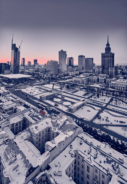 WARSAW, POLAND - JANUARY 31, 2021: Beautiful panoramic aerial drone view on Warsaw City Skyscrapers, PKiN, and Varso Tower under construction and 19th-century tenement houses during the January sunset