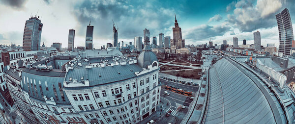 WARSAW, POLAND - February 05, 2021: Beautiful panoramic aerial drone view on Warsaw City Skyscrapers, PKiN, and Varso Tower under construction and 19th-century tenement houses during the february sunset
