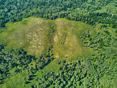 Doğu Kazakistan 'daki Zimovyo yakınlarındaki uçsuz bucaksız Tayga ormanının çarpıcı yüksek açılı panoramik drone görüntüsü. Görüntü, kozalaklı ağaçların sonsuz yeşil gölgesini, dolambaçlı toprak yolu ve soğuk algınlığı ile aydınlık bir yaz gökyüzünün altında uzanan uzak dağ sıralarını yakalıyor.