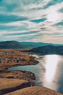 Doğu Kazakistan 'daki Sibinskiye Gölleri' nin çarpıcı yüksek açılı panoramik manzarası. Görüntü, eşsiz, engebeli granit dağ sırtları ve bulutlu gökyüzünün altındaki kaya oluşumları arasında yuva yapmış birkaç derin mavi göl sergiliyor.
