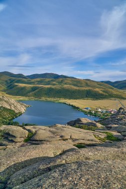 Doğu Kazakistan 'daki Sibinskiye Gölleri' nin çarpıcı yüksek açılı panoramik manzarası. Görüntü, eşsiz, engebeli granit dağ sırtları ve bulutlu gökyüzünün altındaki kaya oluşumları arasında yuva yapmış birkaç derin mavi göl sergiliyor.