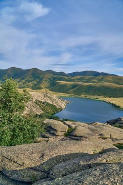 Doğu Kazakistan 'daki Sibinskiye Gölleri' nin çarpıcı yüksek açılı panoramik manzarası. Görüntü, eşsiz, engebeli granit dağ sırtları ve bulutlu gökyüzünün altındaki kaya oluşumları arasında yuva yapmış birkaç derin mavi göl sergiliyor.