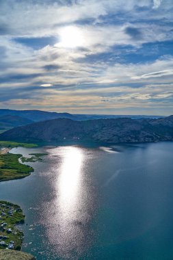Doğu Kazakistan 'daki Sibinskiye Gölleri' nin çarpıcı yüksek açılı panoramik manzarası. Görüntü, eşsiz, engebeli granit dağ sırtları ve bulutlu gökyüzünün altındaki kaya oluşumları arasında yuva yapmış birkaç derin mavi göl sergiliyor.