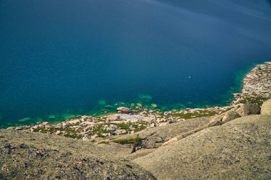 Doğu Kazakistan 'daki Sibinskiye Gölleri' nin çarpıcı yüksek açılı panoramik manzarası. Görüntü, eşsiz, engebeli granit dağ sırtları ve bulutlu gökyüzünün altındaki kaya oluşumları arasında yuva yapmış birkaç derin mavi göl sergiliyor.