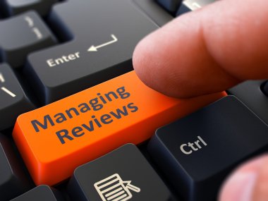 Pressing Orange Button Managing Reviews on Black Keyboard.