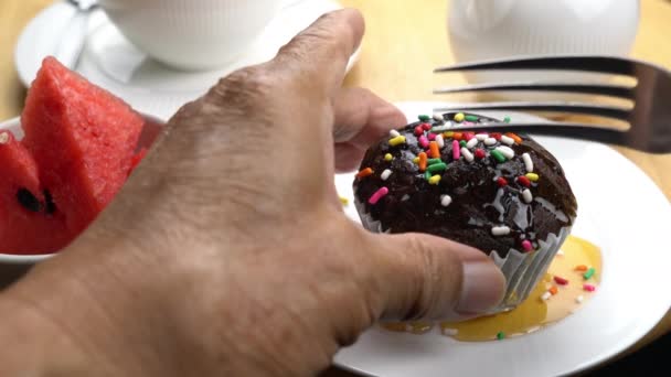 무지개로 토핑하는 케익을 세라믹 접시에 링클스를 먹는다 손위에 머핀을 포크로 — 비디오