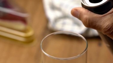 Alüminyum teneke kutudan kolayı ahşap masanın üzerindeki bir bardağa döküyorum. Yaşlı adam bir kutu tutuyor ve bardağa kola dolduruyor..