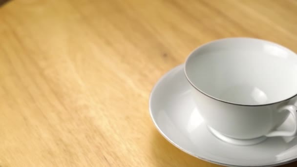 木製のテーブルの上にソーサー付きの白いセラミックカップに黒コーヒーを入れてください 黒コーヒーはモカポットコーヒーメーカーから白いカップに注ぐ — ストック動画