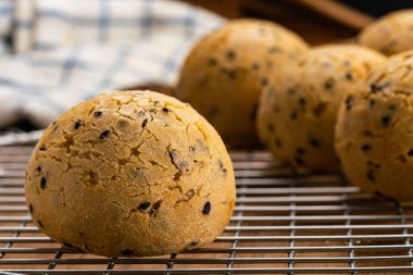 Yakından bakınca taze pişmiş ev yapımı susamlı çörek metal soğutma rafında ve ahşap masada bulaşık bezi..