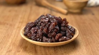 Kurutulmuş kuru üzüm yığınını ahşap tabakta, ahşap masada yakınlaştır..