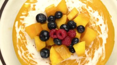 Lezzetli ev yapımı mango peynirli kekten zum yap olgun mango parçalarıyla süslenmiş, ahududu ve yabanmersini ile korunmuş kahverengi seramik tabakta moka demlik kahve makinesi, kürek ve bambu sepeti..
