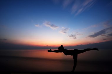 Gün batımında yoga yapan kadın.