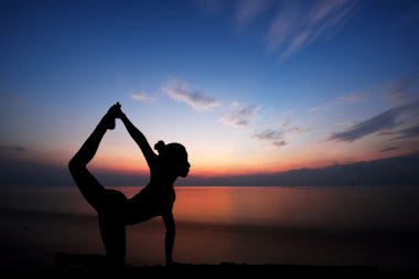 Gün batımında yoga yapan kadın.