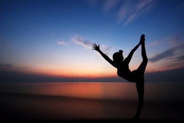 Gün batımında yoga yapan kadın.