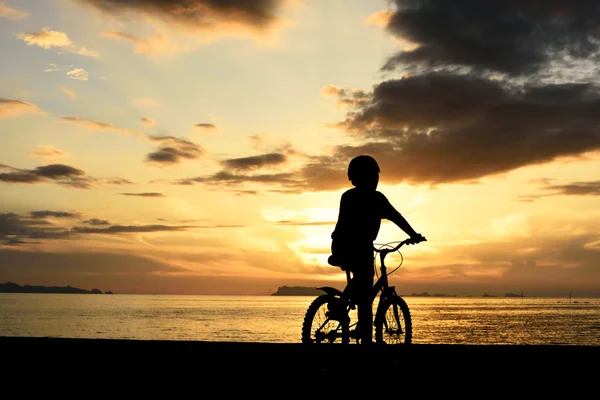 Silueta de niño con bicicleta en la playa — Foto de Stock