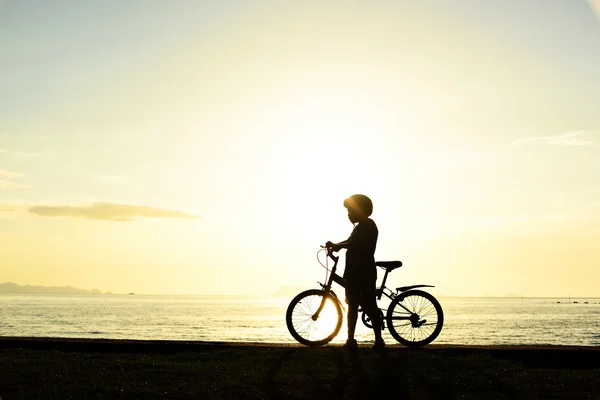 Silhuett av pojke med cykel på stranden — Stockfoto