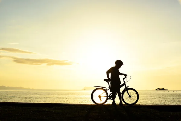 Silhouet van jongen met fiets op strand — Stockfoto