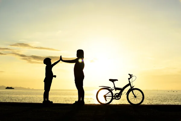 Mamma och pojke med cykel på stranden — Stockfoto