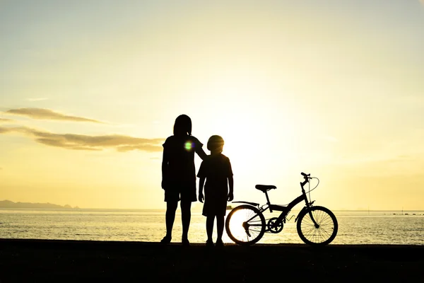 Mamma och pojke med cykel på stranden — Stockfoto