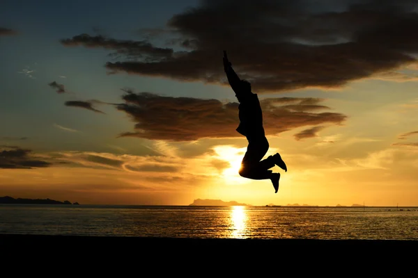 Silhouette of jumping man on beach — Stock Photo, Image